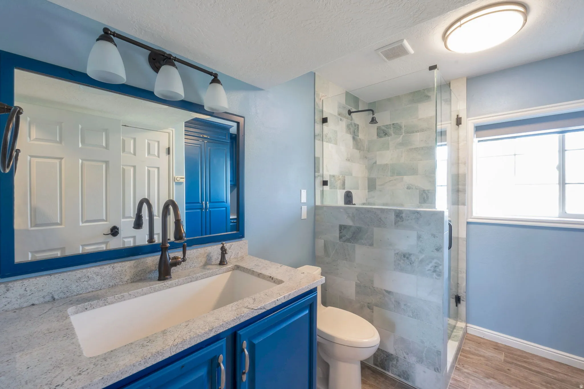 Bathroom featuring a modern vanity with a rectangular basin sink, granite countertop, and blue cabinetry