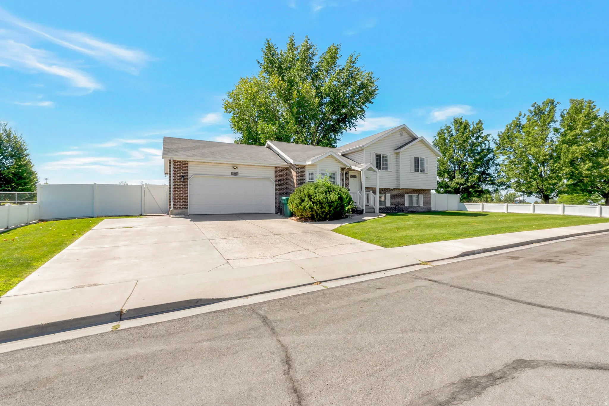 Split-level residence featuring a brick and siding exterior, a two-car garage, and a concrete driveway