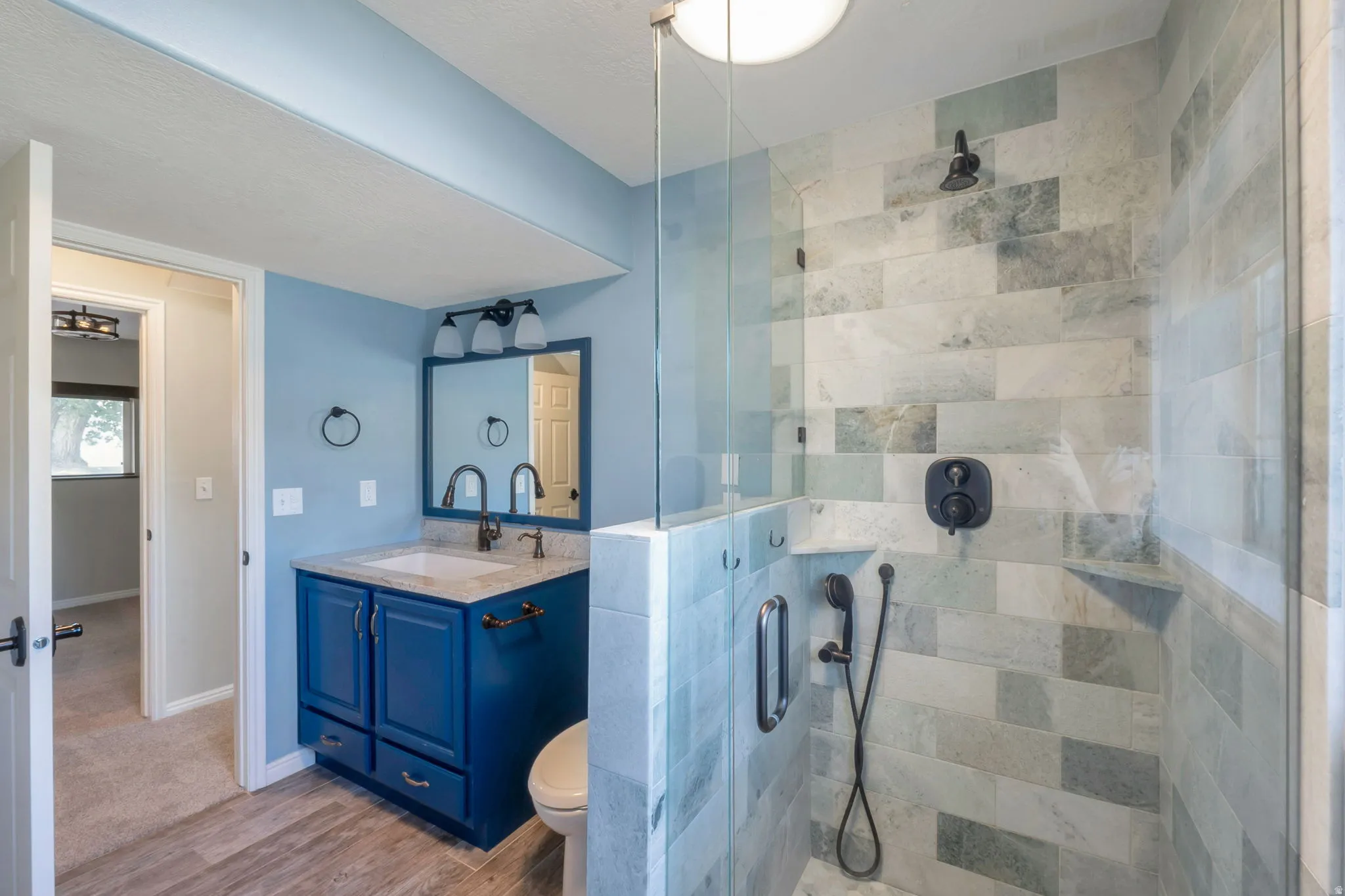 Spacious bathroom featuring a glass-enclosed shower with tiled walls and matte black fixtures