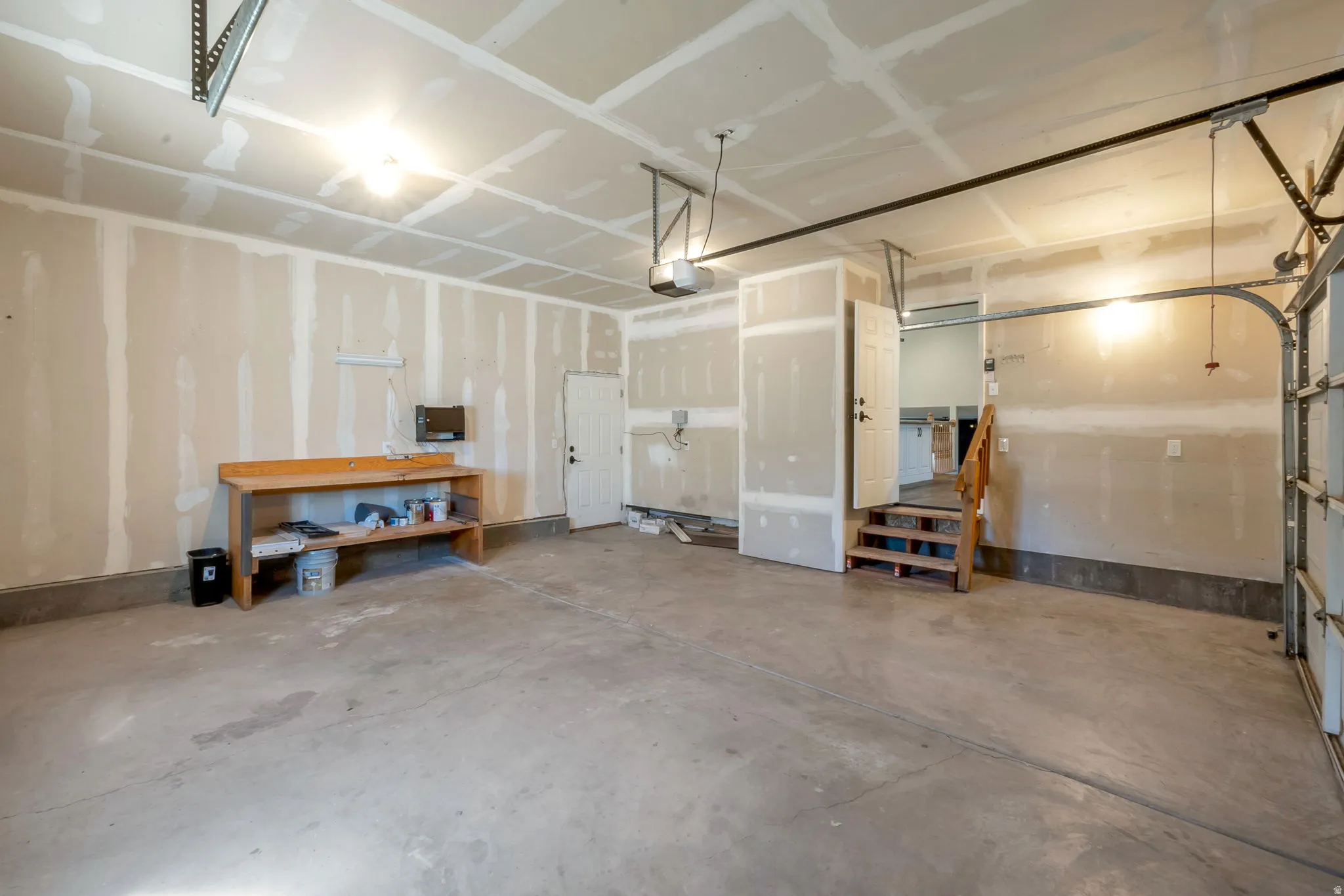 Spacious garage with concrete flooring, exposed drywall, and overhead lighting