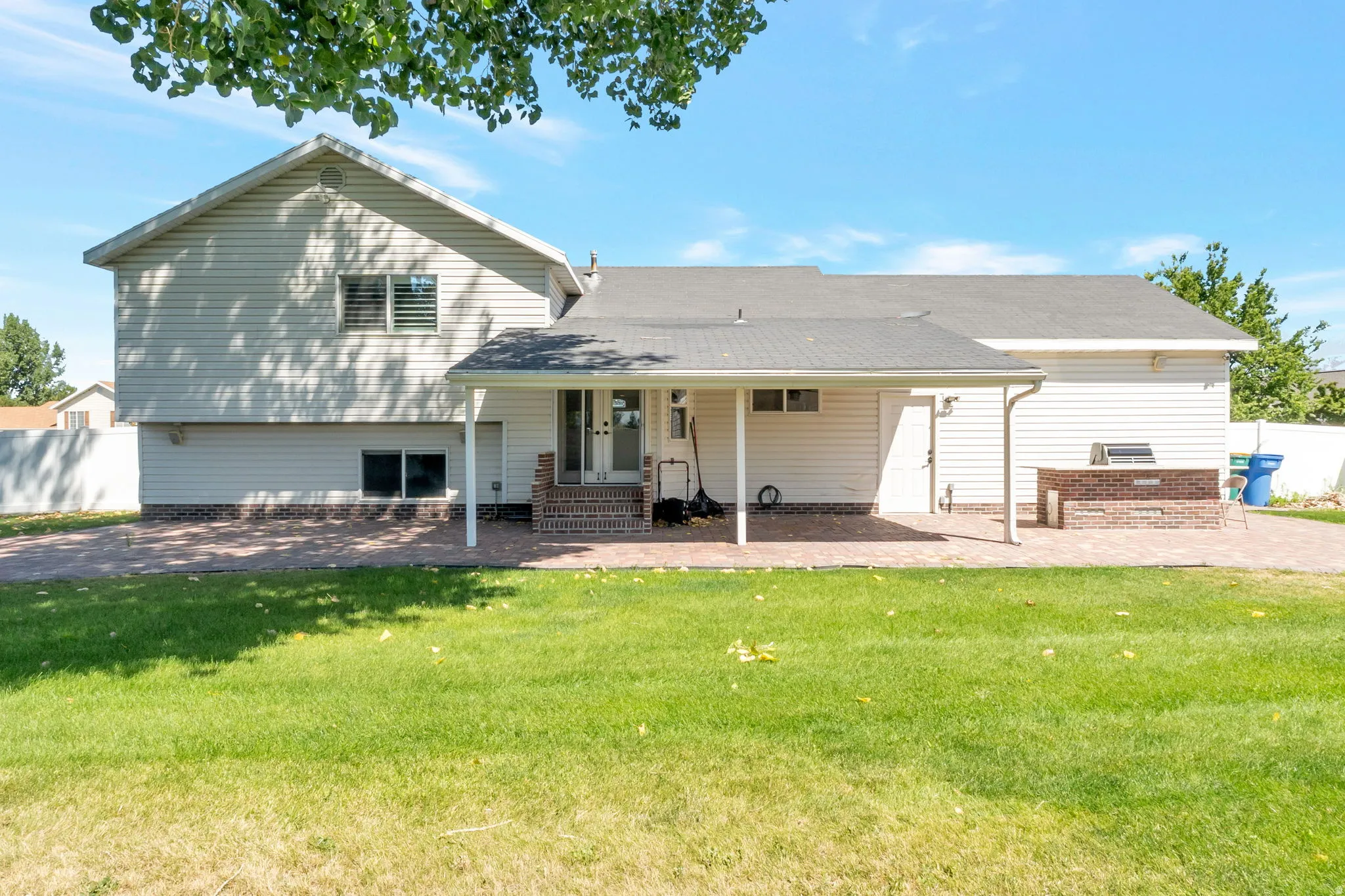 Expansive rear patio featuring brick pavers and a covered outdoor living area