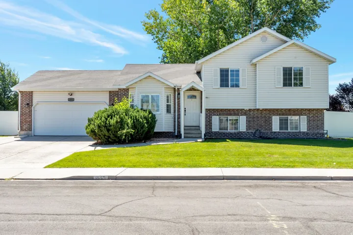 Split-level residence featuring a brick and siding facade, attached two-car garage, manicured front lawn, and concrete driveway