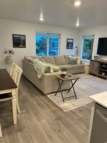 Open-concept living area featuring wood-finish flooring, recessed ceiling lighting, and multiple windows