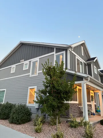Contemporary multi-story facade featuring mixed siding, stone veneer accents, white trim, and multiple windows