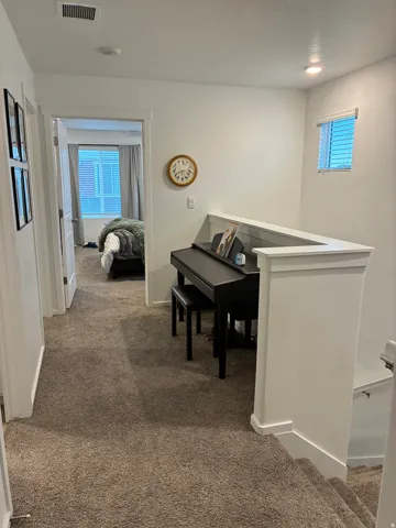 Carpeted hallway with white walls and trim, recessed lighting, and a window with blinds