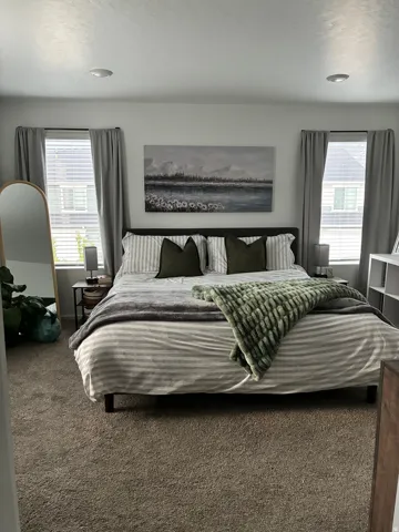 Spacious bedroom featuring neutral carpet, recessed lighting, and two windows with blinds