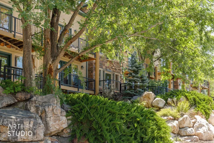 Multi-level building exterior featuring balconies with black metal railings, stone and stucco siding, and double glass doors