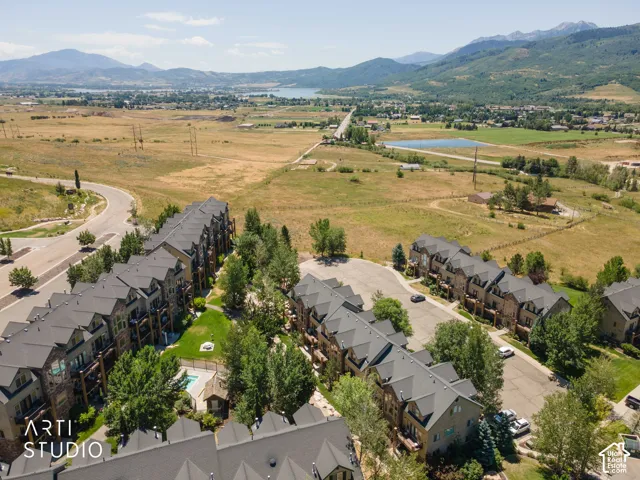 Expansive community featuring multi-story townhomes with dark roofing and stone facades