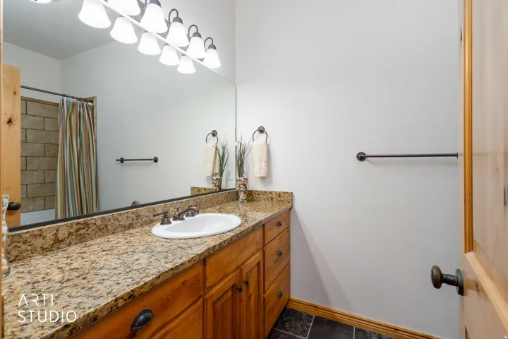 Bathroom featuring a light wood vanity with an integrated sink, granite countertop, and dark bronze hardware
