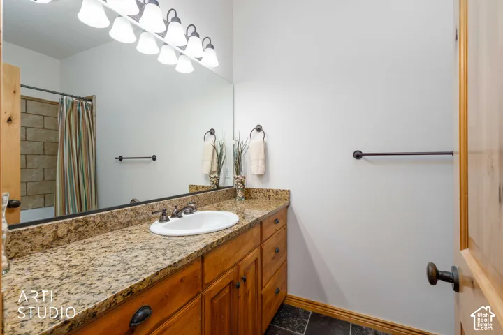 Bathroom featuring a light wood vanity with an integrated sink, granite countertop, and dark bronze hardware