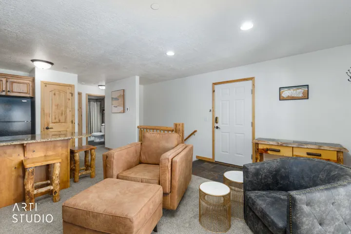 Open-concept living space featuring a breakfast bar with granite-look countertops, warm wood-finish cabinetry, and recessed lighting