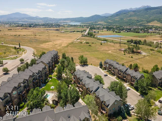 Expansive community featuring multi-story townhomes with dark roofing and stone facades