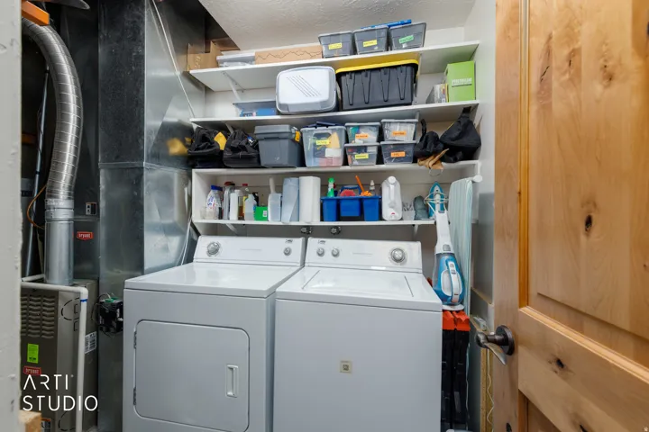 Utility area featuring a washer, dryer, built-in shelving, and a natural wood-finish door with dark hardware