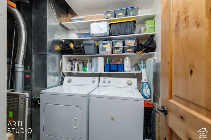 Utility area featuring a washer, dryer, built-in shelving, and a natural wood-finish door with dark hardware