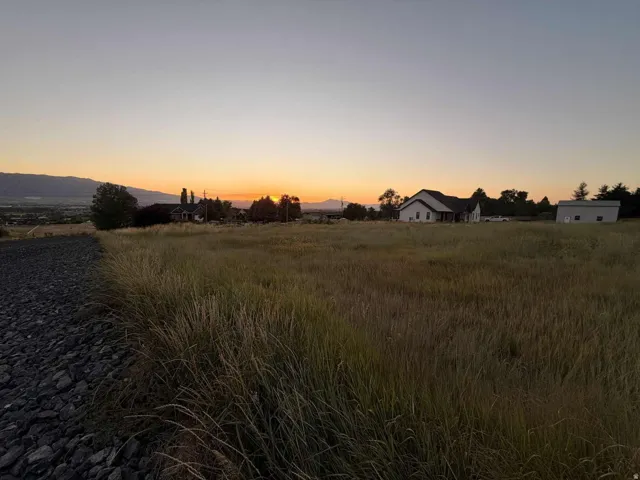 Expansive open field with scattered buildings and distant mountains