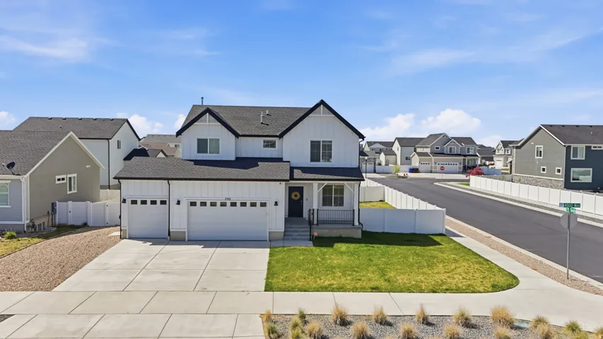 Modern farmhouse-style exterior featuring white siding with black trim accents, a dark shingle roof, and a covered front porch