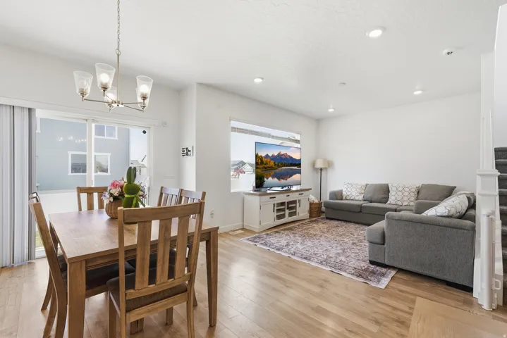 Open-concept living space featuring wood-finish flooring, recessed lighting, and a modern chandelier