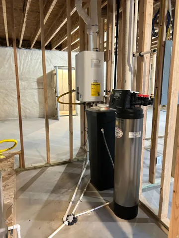 Utility area featuring a tankless water heater, water softener system, and PEX plumbing