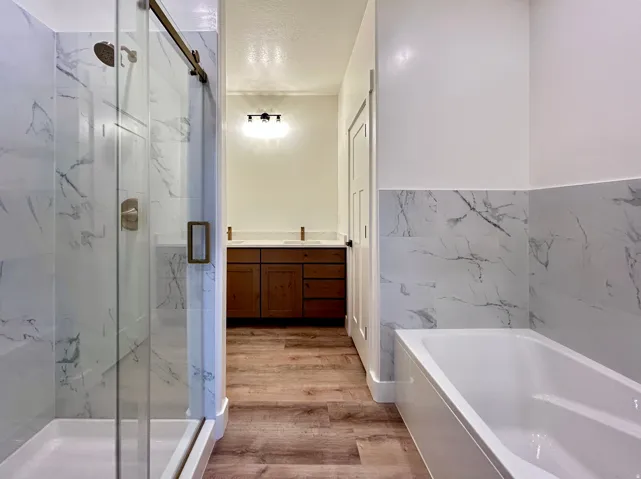 Walk-in shower with a glass sliding door, brushed nickel fixtures, and white marble-look tile