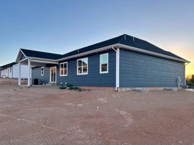 Contemporary ranch-style residence featuring deep blue siding and a dark shingle roof