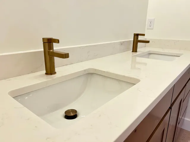 Dual undermount sinks set within a light-toned countertop with integrated backsplash