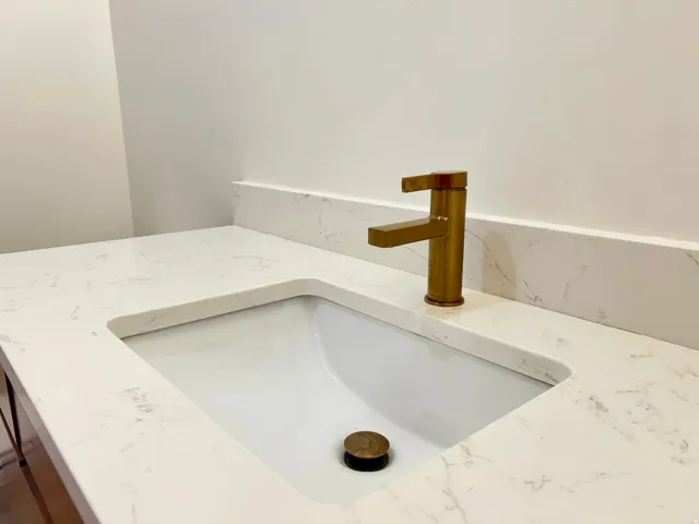Integrated vanity sink with a white basin and a brass-finish faucet
