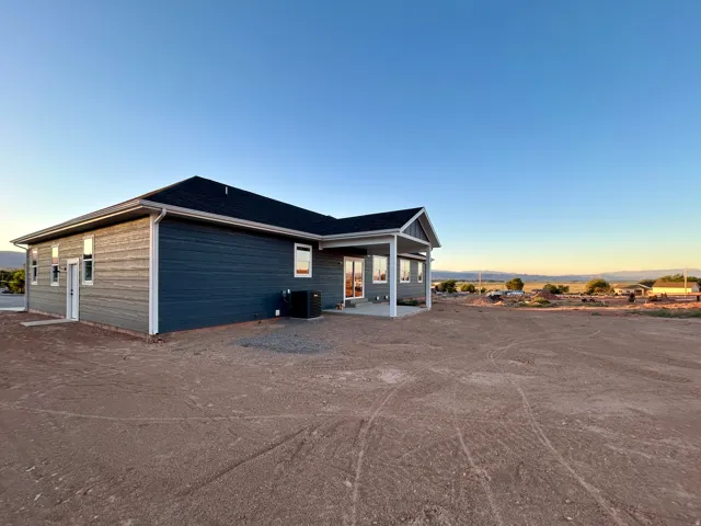 Modern residence featuring dark blue siding, white trim, and a covered patio area