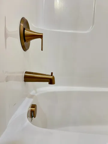 Shower and bathtub combination with bronze-finish fixtures and a single-handle faucet