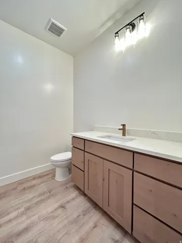 Contemporary vanity with light wood-finish cabinetry, white countertop, and integrated sink