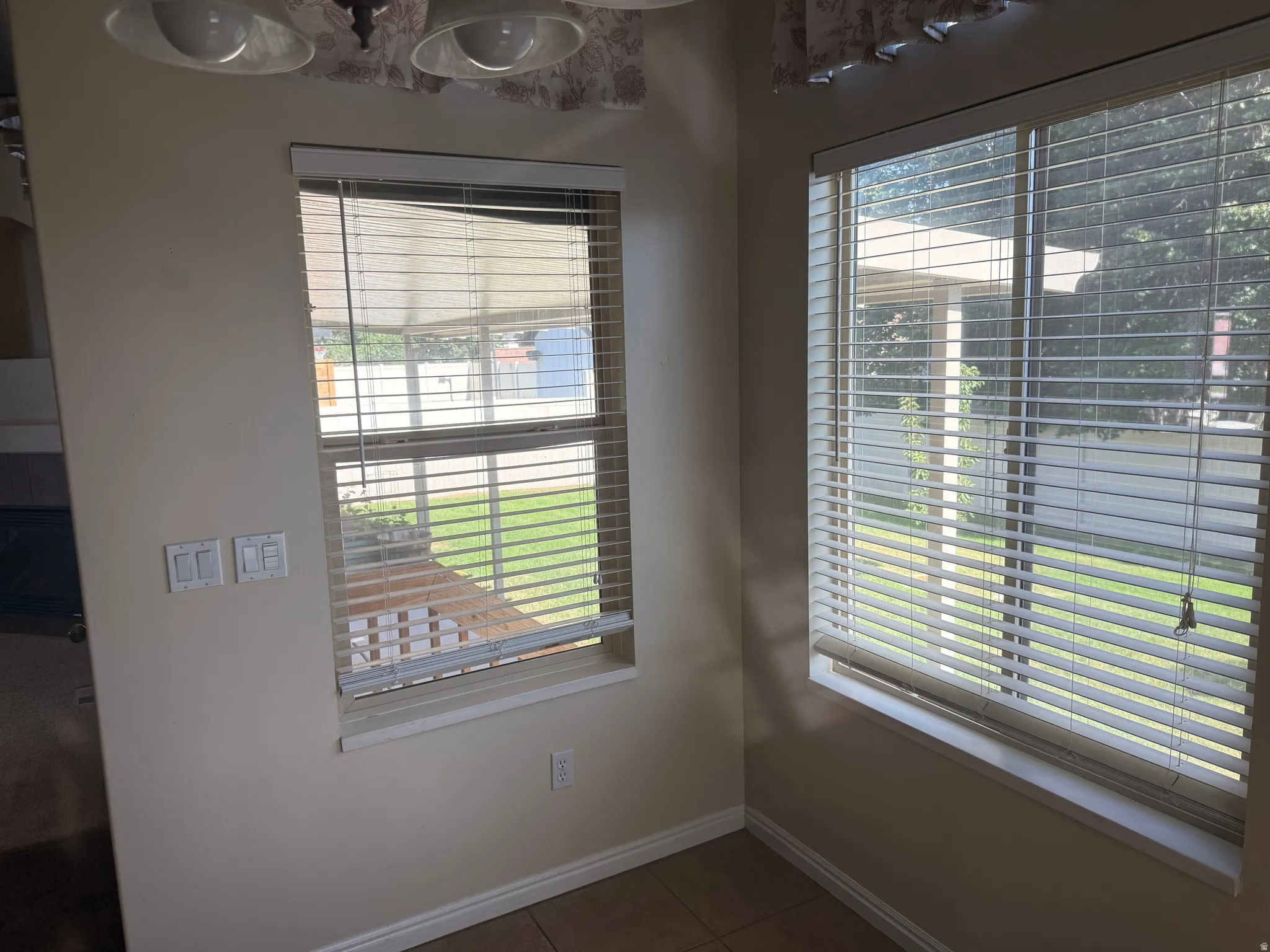 Corner window composition featuring a larger window with horizontal blinds and a smaller window with both horizontal blinds and a privacy shade