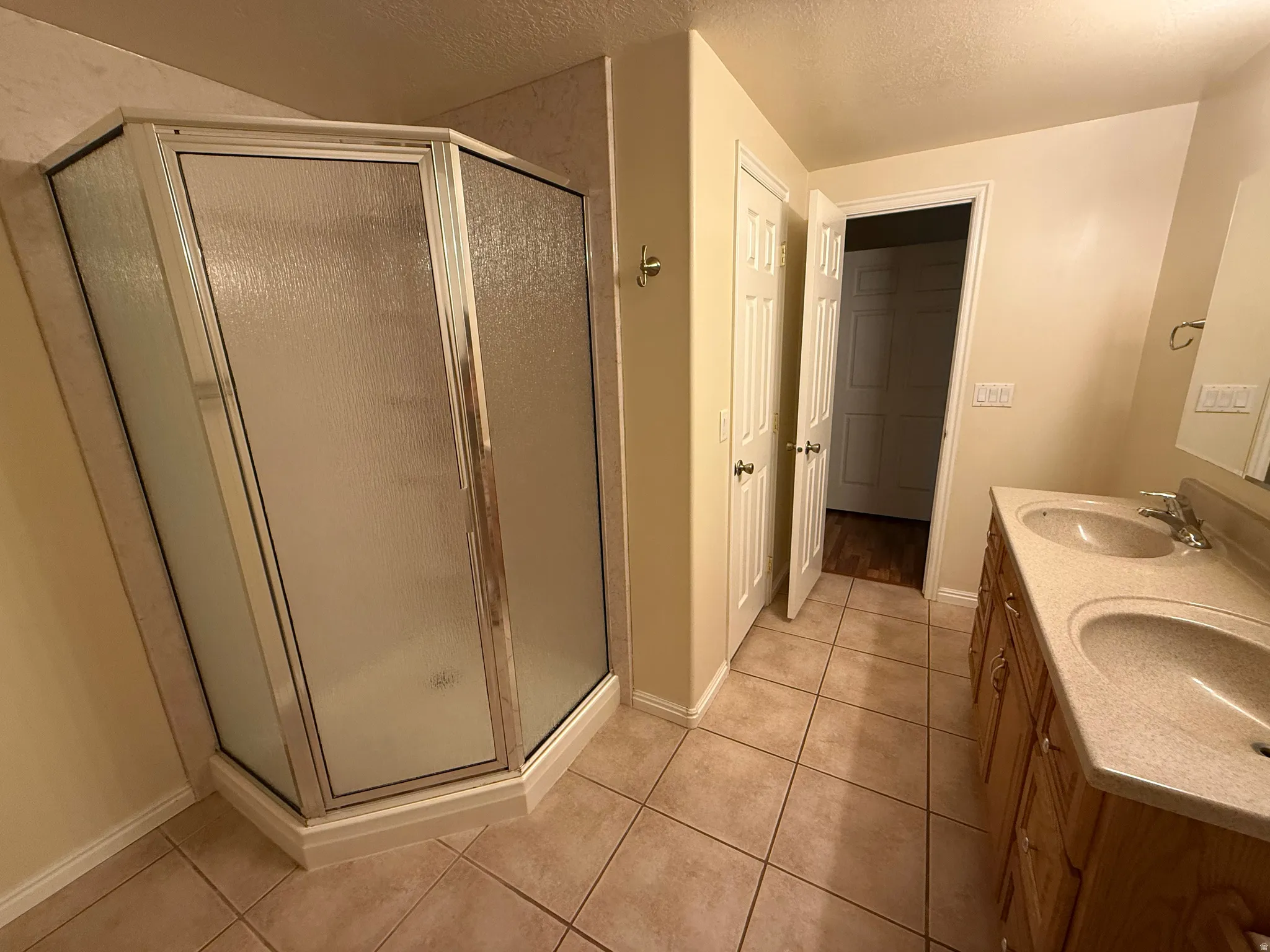 Shower enclosure with frosted glass panels, accompanied by a double vanity featuring integrated sinks and a neutral countertop
