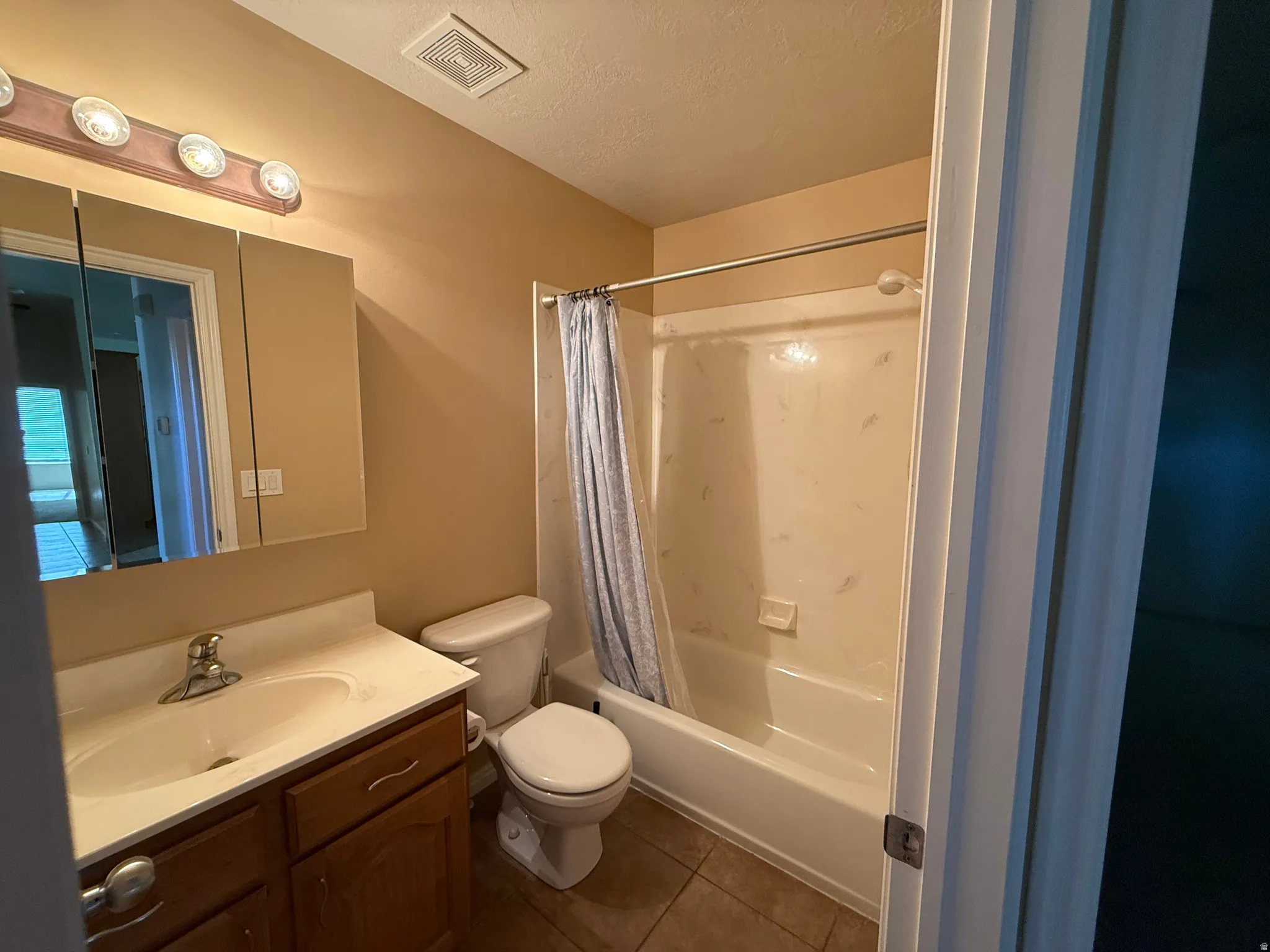 Full bathroom featuring a single vanity with wood-finish cabinetry, a white countertop with integrated sink, and a combination shower and tub
