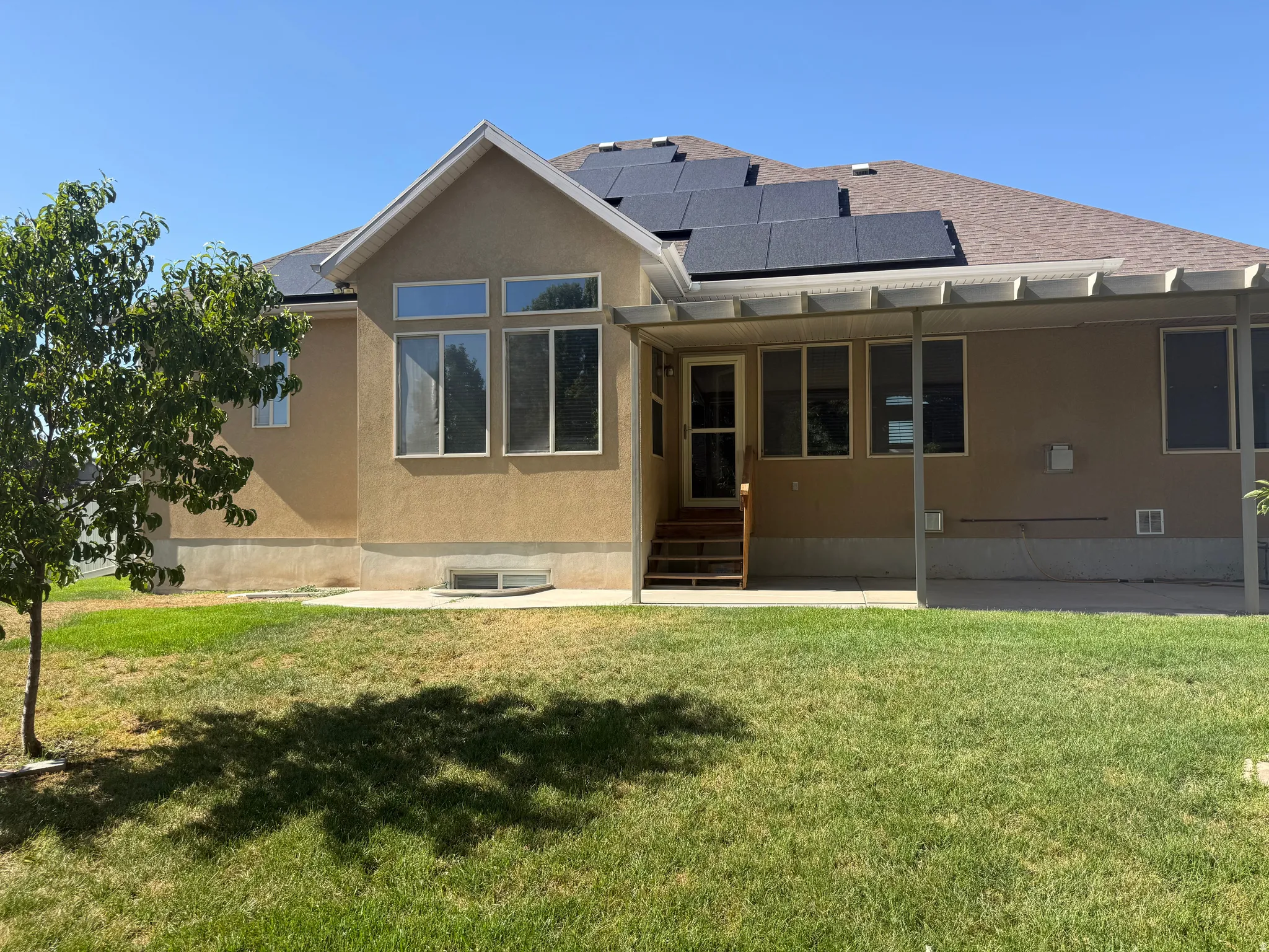 Rear exterior featuring a covered patio, multiple windows, and solar panels on the roof