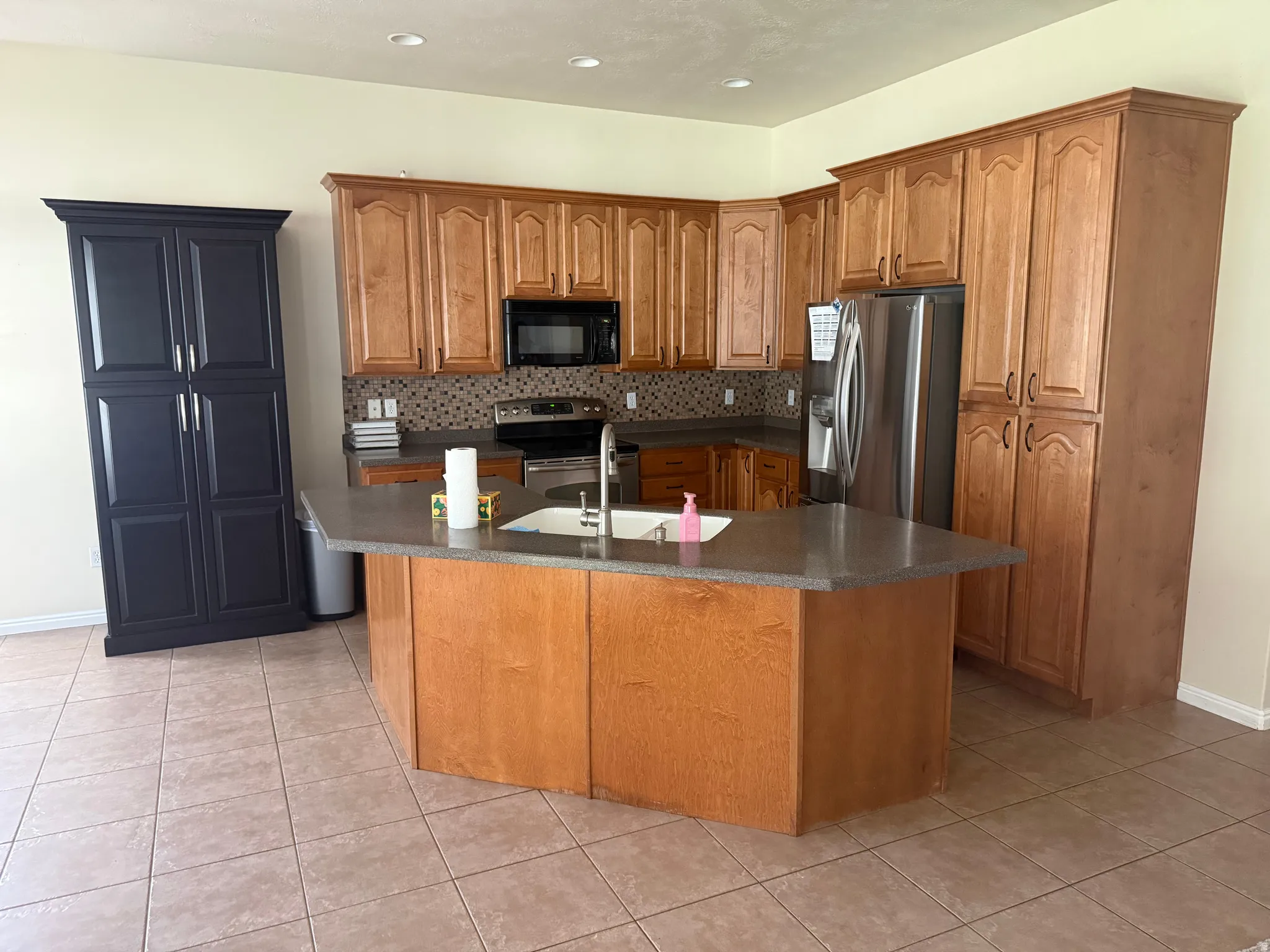 Kitchen featuring wood cabinetry, stone-look countertops, and a mosaic tile backsplash