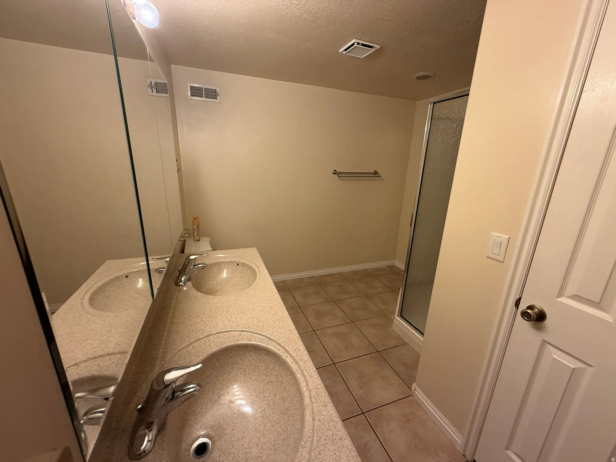 Dual basin vanity with speckled countertop, chrome fixtures, and a frameless mirror
