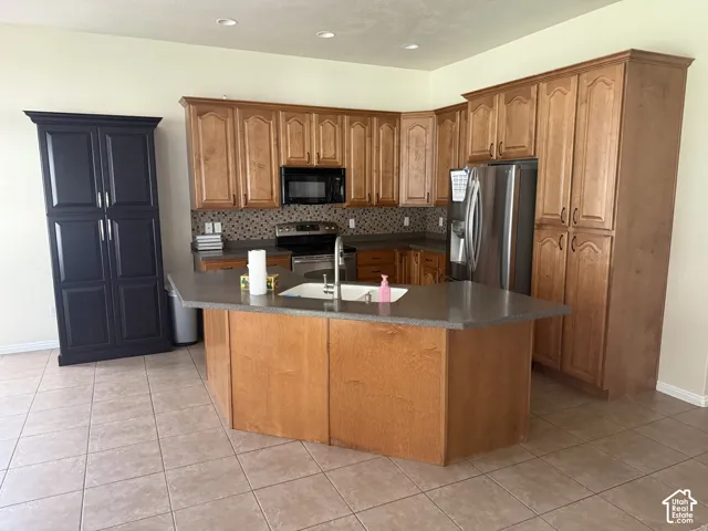 Kitchen featuring wood cabinetry, stone-look countertops, and a mosaic tile backsplash