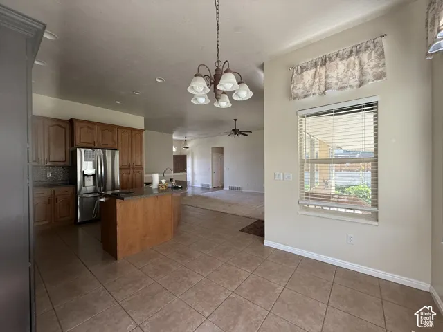 Kitchen featuring wood cabinetry, a center island with countertop, stainless steel refrigerator, and tiled flooring