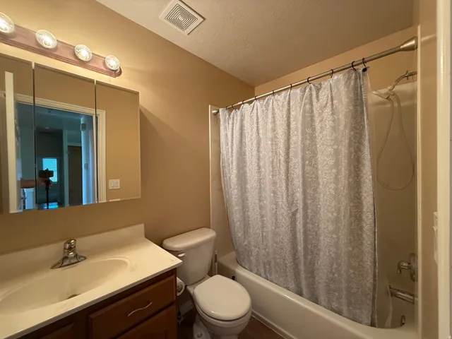 Bathroom featuring a vanity with a white countertop, wood-finish cabinetry, built-in medicine cabinet, and a full-size bathtub with a shower