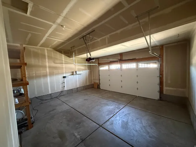 Two-car garage with unfinished walls, concrete flooring, and an automatic overhead door with transom window inserts