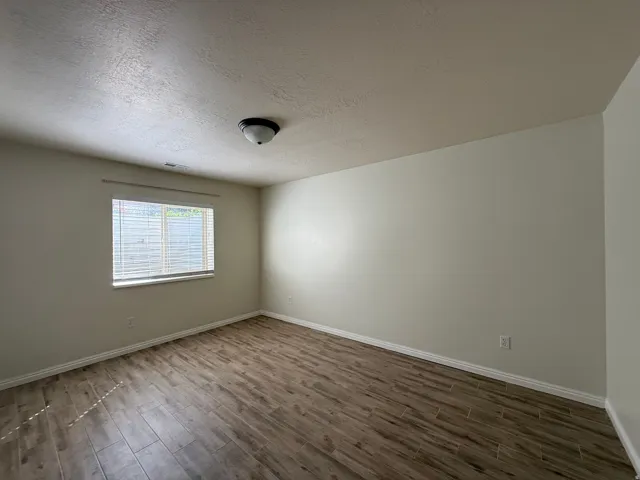 Neutral wall paint, wood-finish flooring, and window with blinds