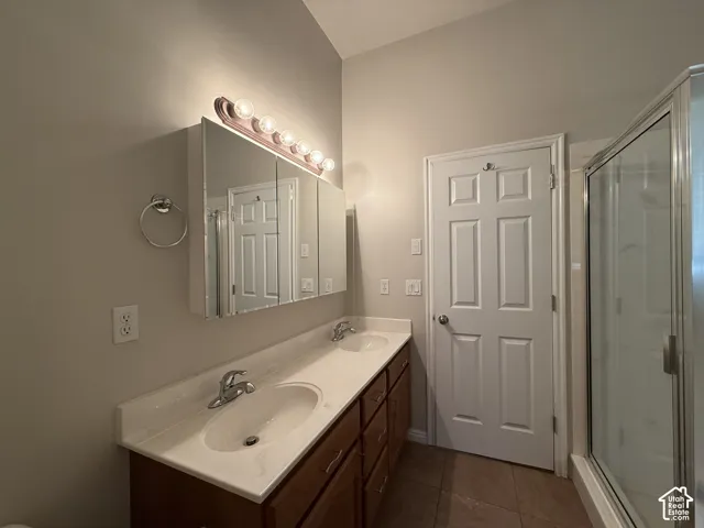 Dual vanity with integrated sinks, wood-finish cabinetry, and an overhead mirror with task lighting