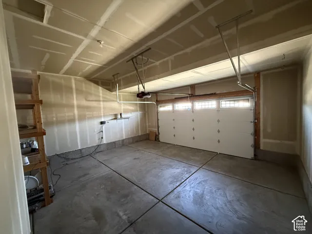 Two-car garage with unfinished walls, concrete flooring, and an automatic overhead door with transom window inserts