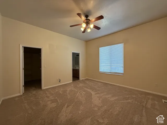 Spacious room with plush carpeting, a multi-light ceiling fan, and a large window with horizontal blinds