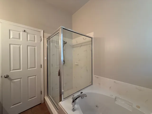 Shower enclosure with glass panels and a built-in bathtub with a deck-mounted faucet