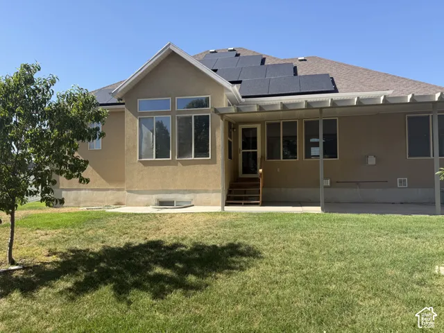 Rear exterior featuring a covered patio, multiple windows, and solar panels on the roof