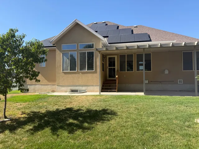 Rear exterior featuring a covered patio, multiple windows, and solar panels on the roof