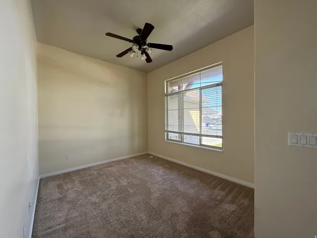 Wall-to-wall carpeting, overhead ceiling fan with lighting, and a large window with horizontal blinds