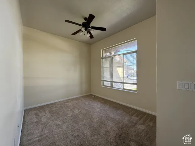 Wall-to-wall carpeting, overhead ceiling fan with lighting, and a large window with horizontal blinds