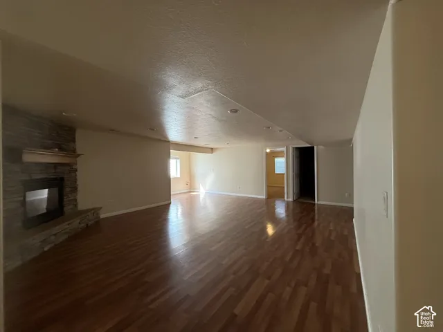 Recessed lighting, wood-finish flooring, stone-clad fireplace, and a wood mantel