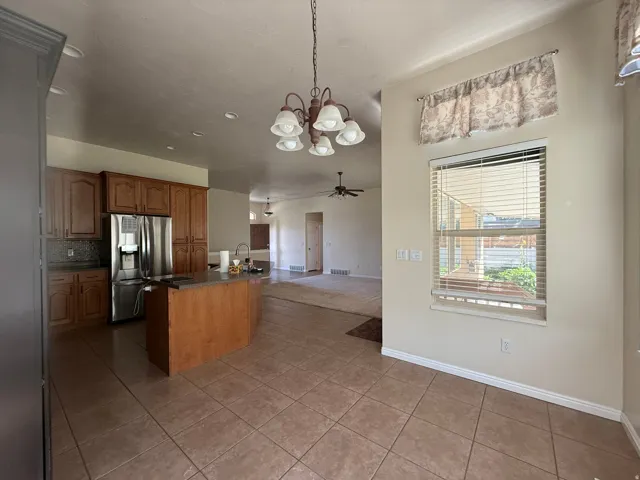 Kitchen featuring wood cabinetry, a center island with countertop, stainless steel refrigerator, and tiled flooring